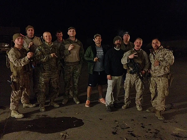 Troops with collation forces and civilian contractors enjoying cigars from Cigars International at a camp in Iraq.